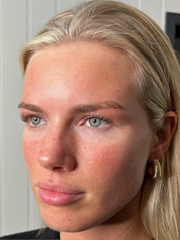 A client with glowing, natural makeup — softly defined brows and a fresh, radiant complexion.